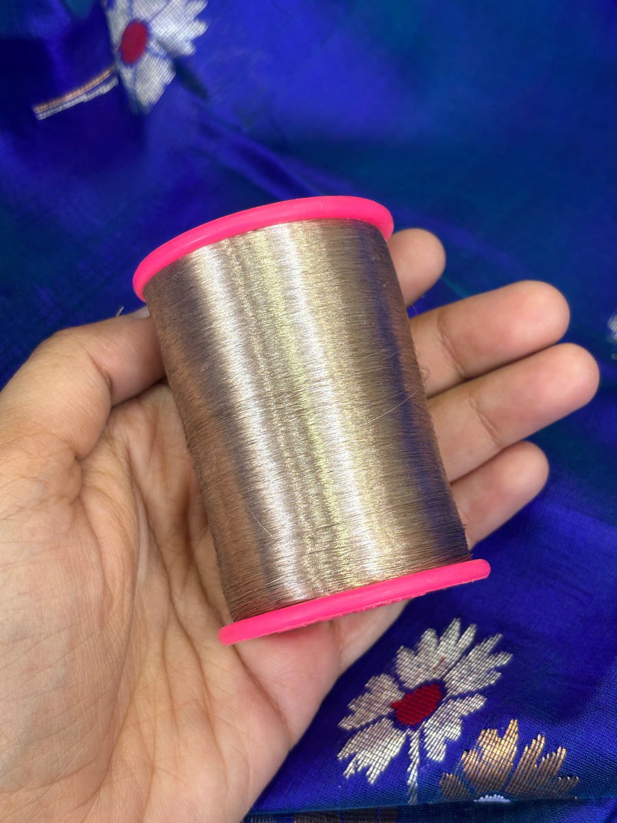 A spool of zari held against woven Chanderi cloth